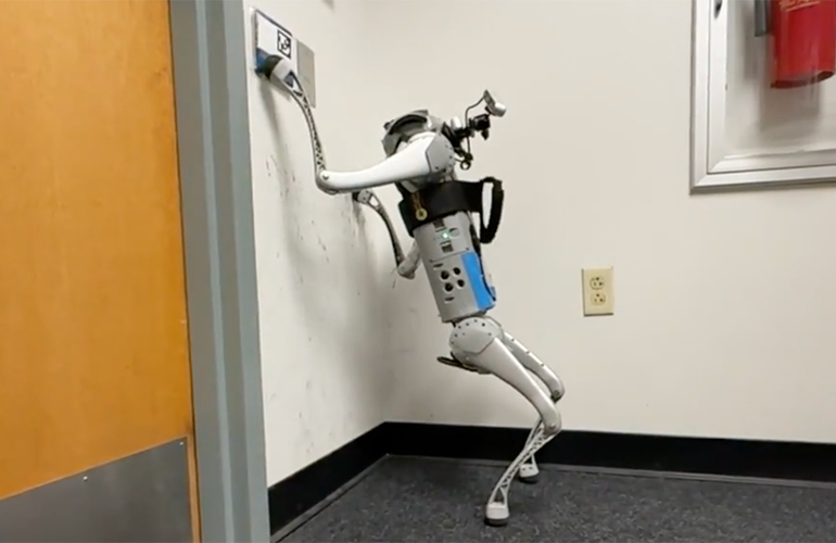 A quadruped robot leaning against a wall and touching a button.