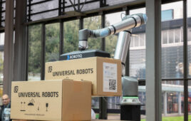 A Universal Robots cobot with a Robotiq gripper lifting a box.